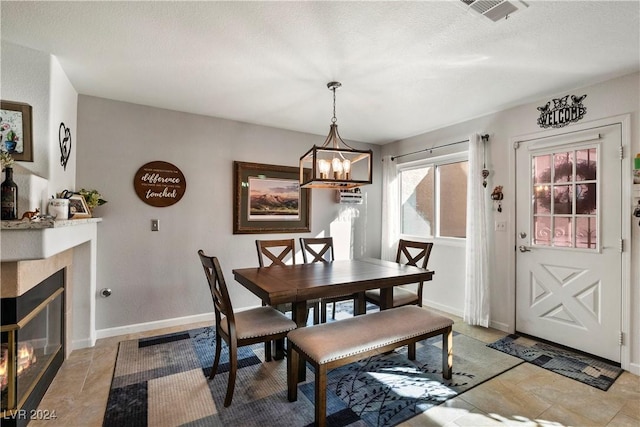 dining space with a tile fireplace, a textured ceiling, and a notable chandelier