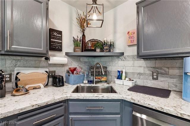 kitchen featuring gray cabinetry, backsplash, sink, stainless steel dishwasher, and decorative light fixtures