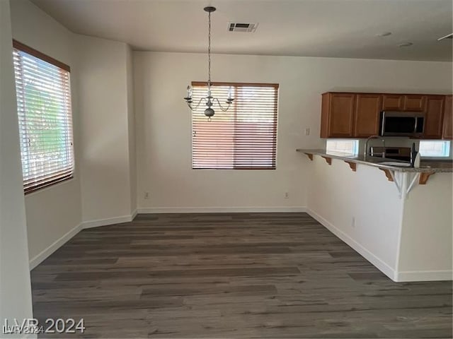 unfurnished dining area with a chandelier and dark hardwood / wood-style flooring