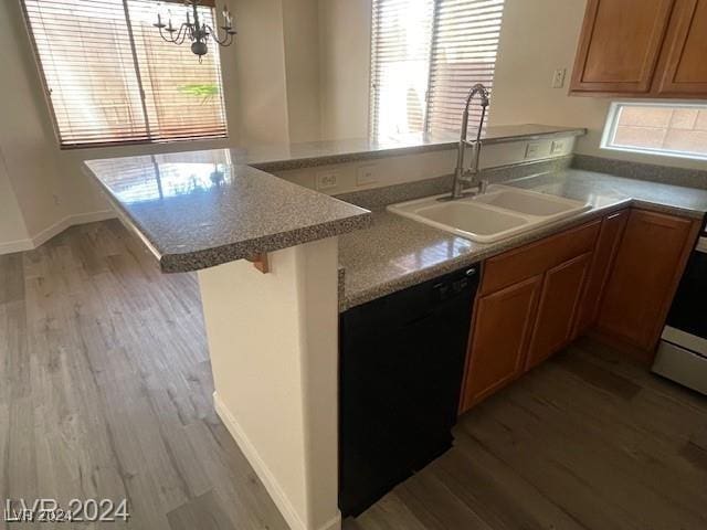 kitchen featuring a kitchen breakfast bar, sink, black dishwasher, light hardwood / wood-style floors, and kitchen peninsula