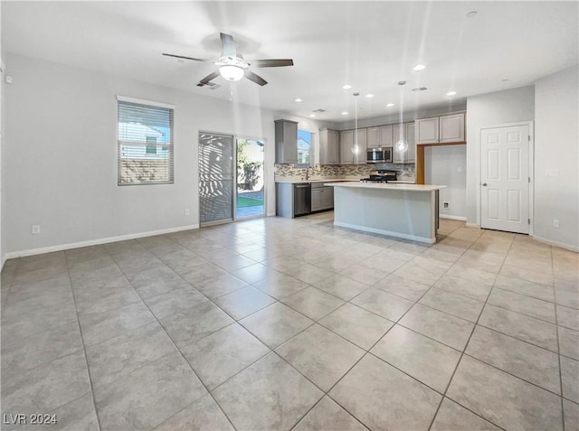 kitchen featuring a center island, ceiling fan, gray cabinets, appliances with stainless steel finishes, and decorative light fixtures