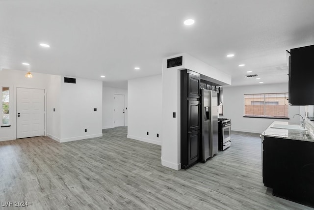 kitchen featuring light hardwood / wood-style floors, light stone counters, sink, and appliances with stainless steel finishes