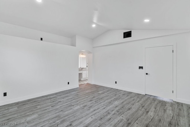 spare room featuring light wood-type flooring and lofted ceiling