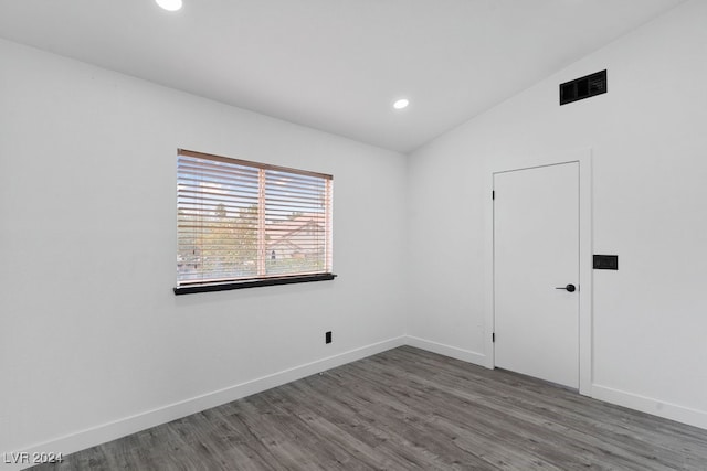 spare room featuring dark hardwood / wood-style flooring and lofted ceiling