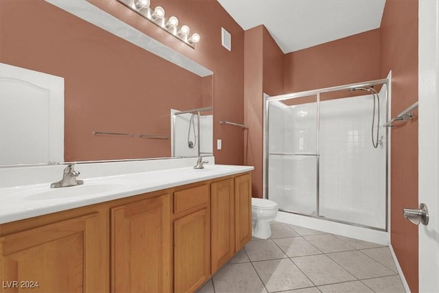 bathroom with tile patterned flooring, vanity, a shower with shower door, and toilet