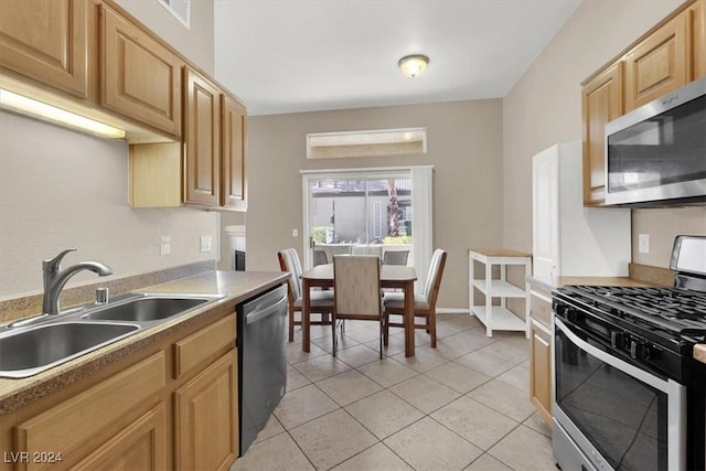 kitchen with appliances with stainless steel finishes, light brown cabinets, light tile patterned floors, and sink