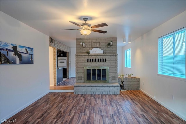 unfurnished living room with a fireplace, ceiling fan, and dark wood-type flooring