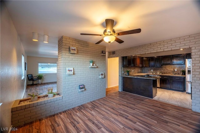 kitchen with brick wall, wood-type flooring, dark brown cabinetry, and stainless steel fridge with ice dispenser