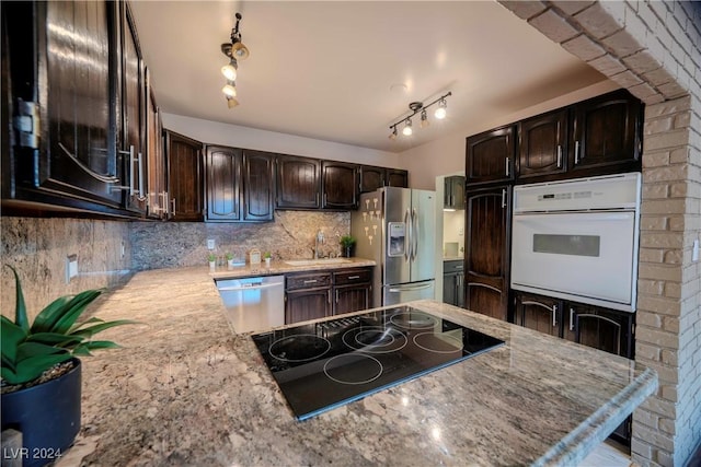 kitchen with dark brown cabinetry, decorative backsplash, rail lighting, and stainless steel appliances