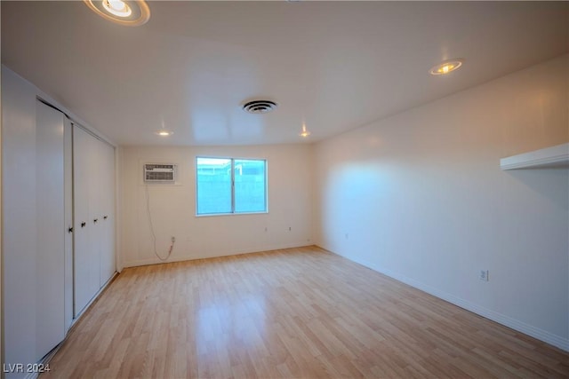 empty room with light hardwood / wood-style floors and a wall mounted AC