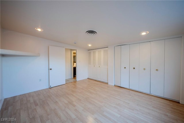 unfurnished bedroom with multiple closets and light hardwood / wood-style flooring