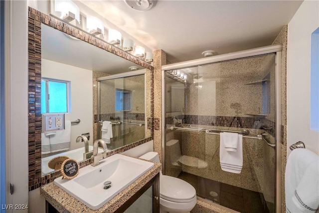 bathroom featuring vanity, toilet, and a shower with shower door