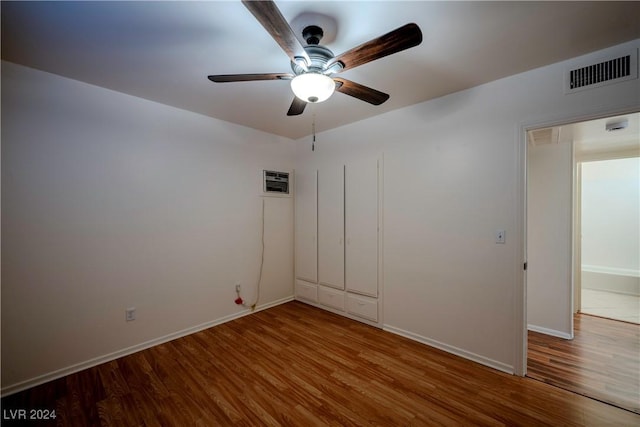 unfurnished room featuring an AC wall unit, ceiling fan, and wood-type flooring