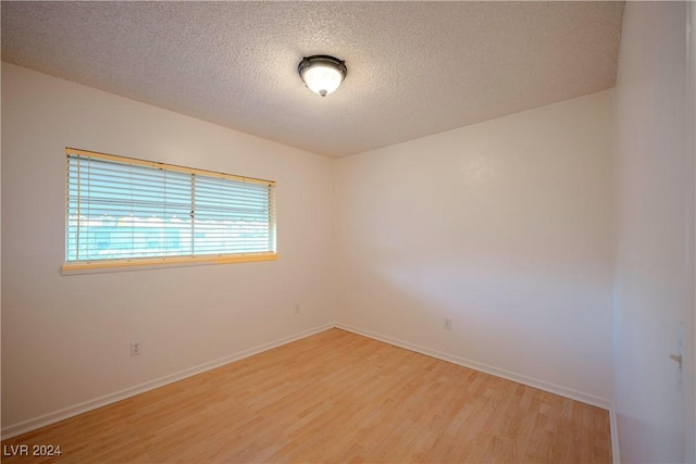 empty room with a textured ceiling and light wood-type flooring