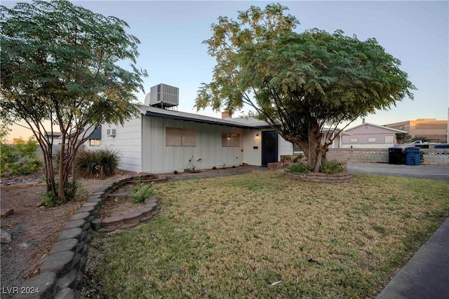 single story home with a yard and central AC unit