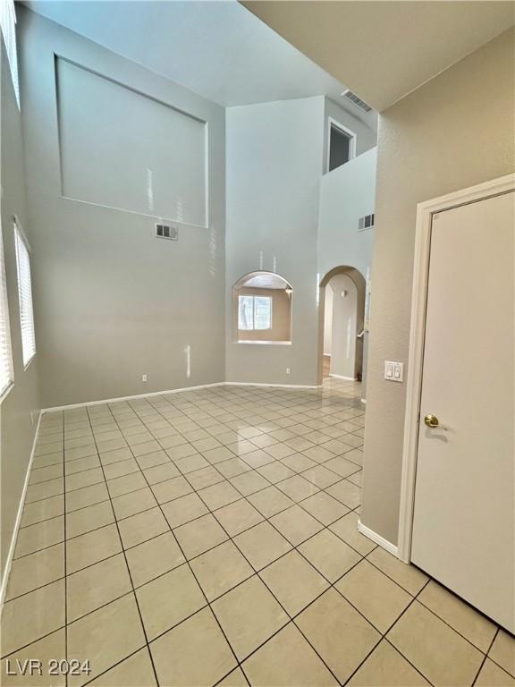 empty room featuring a towering ceiling and light tile patterned flooring