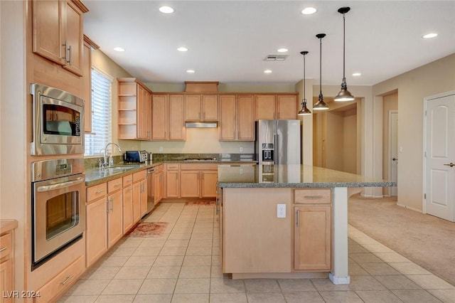 kitchen with light carpet, stainless steel appliances, sink, light brown cabinets, and a center island