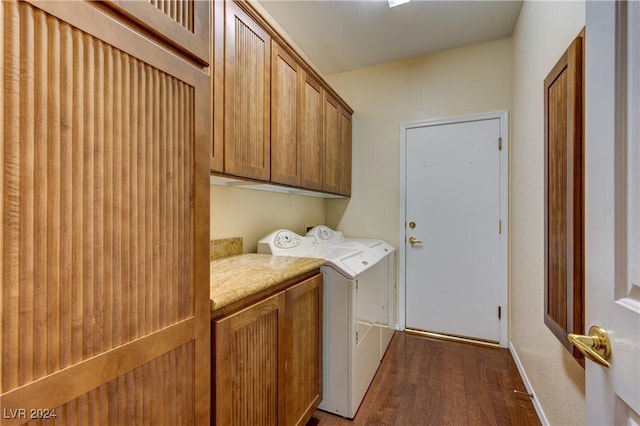 laundry room featuring cabinets, dark wood-type flooring, and washing machine and clothes dryer