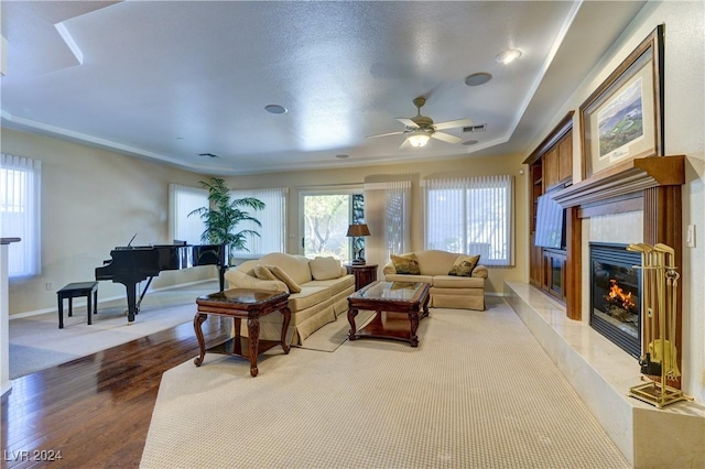 living room with a premium fireplace, ceiling fan, and light wood-type flooring