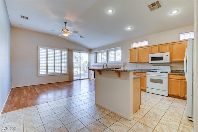 kitchen featuring a breakfast bar, white appliances, lofted ceiling, stone counters, and light hardwood / wood-style floors