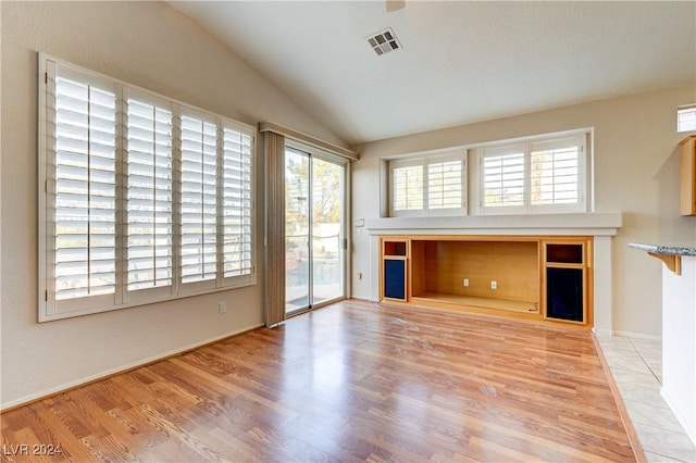 unfurnished living room featuring lofted ceiling and light wood-type flooring