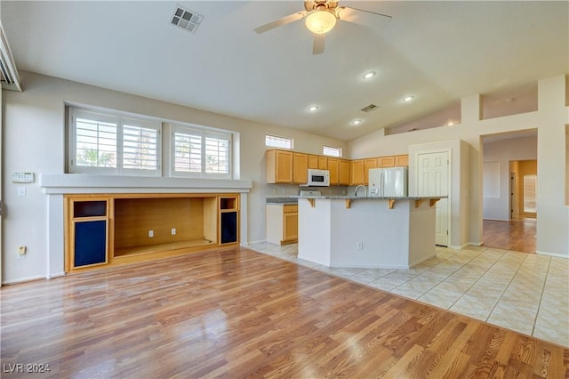 kitchen featuring a kitchen bar, white appliances, a center island, and light hardwood / wood-style flooring