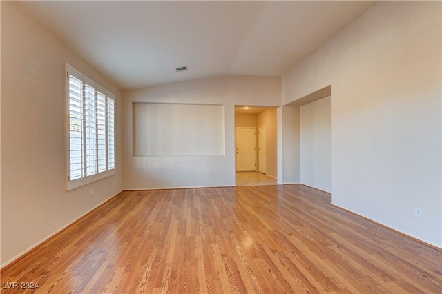 unfurnished room with lofted ceiling and light wood-type flooring