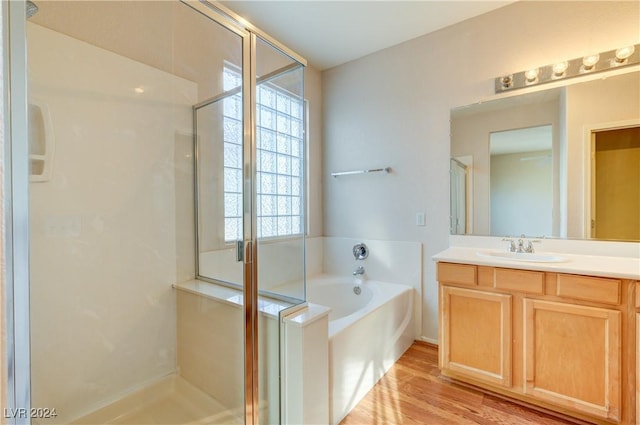 bathroom featuring wood-type flooring, vanity, and shower with separate bathtub