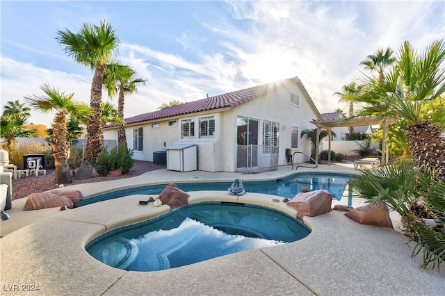 back of property featuring a swimming pool with hot tub, a patio, and central AC