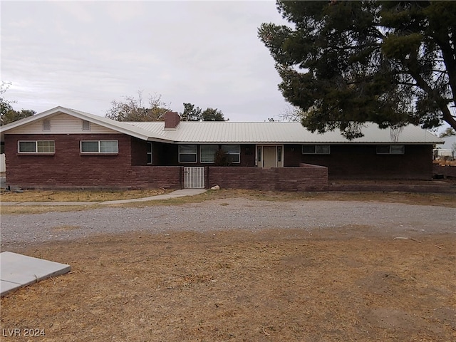 single story home with a chimney, driveway, and metal roof