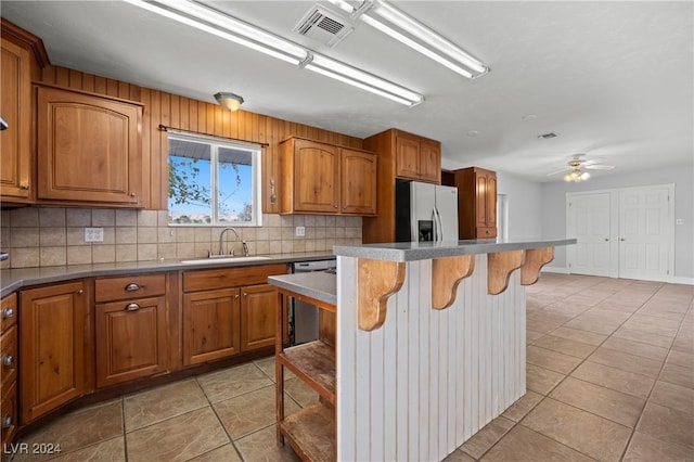 kitchen with a breakfast bar, backsplash, sink, ceiling fan, and stainless steel appliances