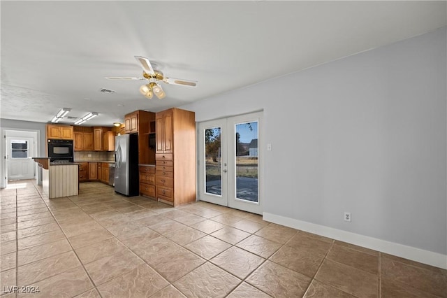 kitchen featuring a center island, french doors, ceiling fan, a kitchen bar, and stainless steel refrigerator