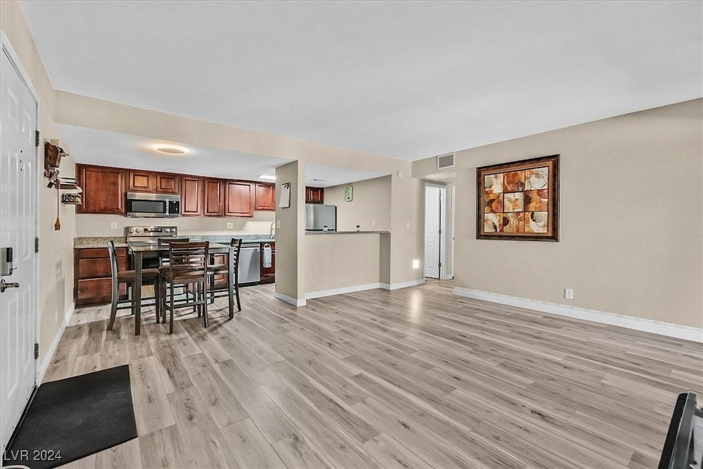 kitchen featuring a kitchen breakfast bar, stainless steel appliances, and light wood-type flooring