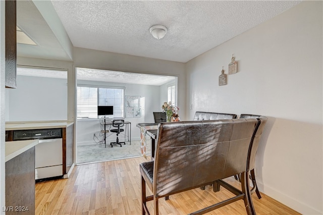 dining space featuring light wood-type flooring and a textured ceiling