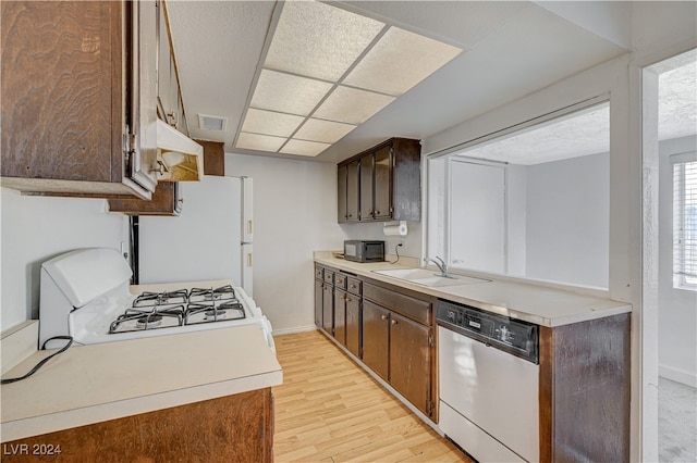 kitchen featuring dark brown cabinetry, sink, light hardwood / wood-style floors, and white appliances