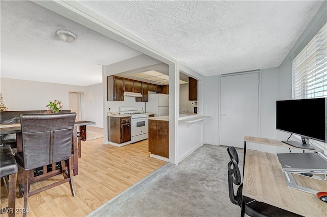 kitchen featuring a textured ceiling, light hardwood / wood-style flooring, and white appliances