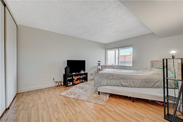 bedroom featuring a closet, a textured ceiling, and light hardwood / wood-style flooring