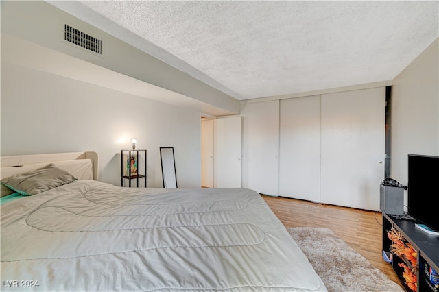 bedroom with light hardwood / wood-style floors and a textured ceiling