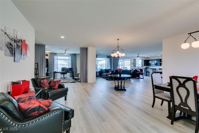 living area with light wood-type flooring, recessed lighting, and ceiling fan with notable chandelier