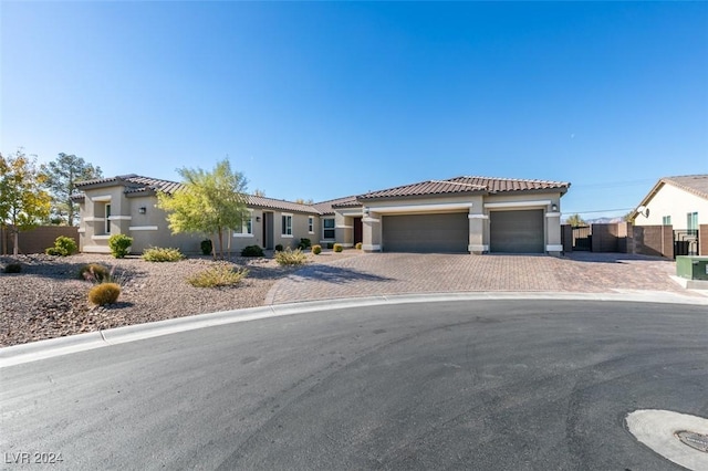 view of front facade featuring an attached garage, fence, a tiled roof, decorative driveway, and stucco siding