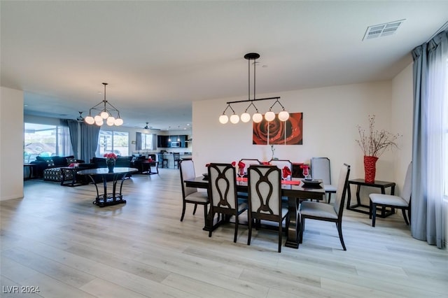 dining space with light hardwood / wood-style flooring and a notable chandelier