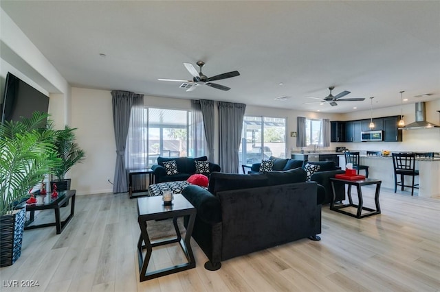 living area featuring light wood-style floors, ceiling fan, and baseboards