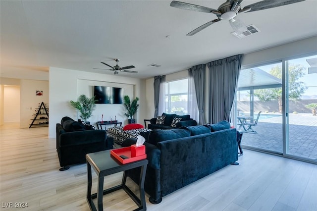 living room featuring light wood-type flooring, visible vents, and ceiling fan