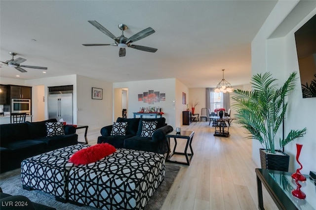 living room with ceiling fan with notable chandelier and light hardwood / wood-style floors