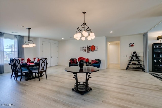 dining space with light hardwood / wood-style flooring and a notable chandelier