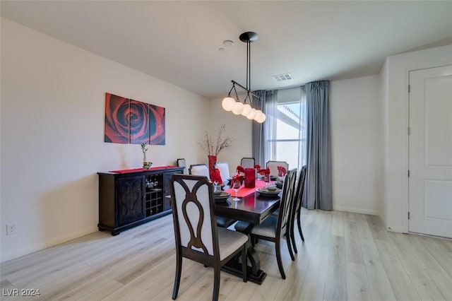 dining area featuring light wood finished floors, baseboards, and visible vents