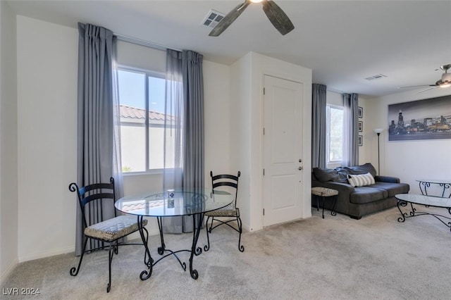 dining space featuring ceiling fan and light colored carpet