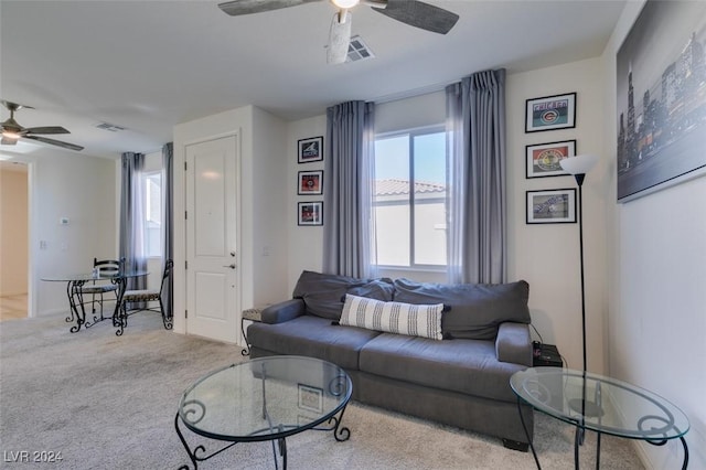 living area with carpet, visible vents, and a ceiling fan