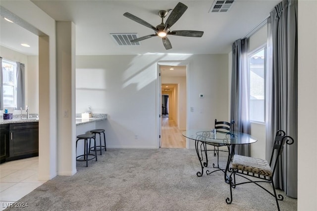 carpeted dining area with ceiling fan, a healthy amount of sunlight, and sink