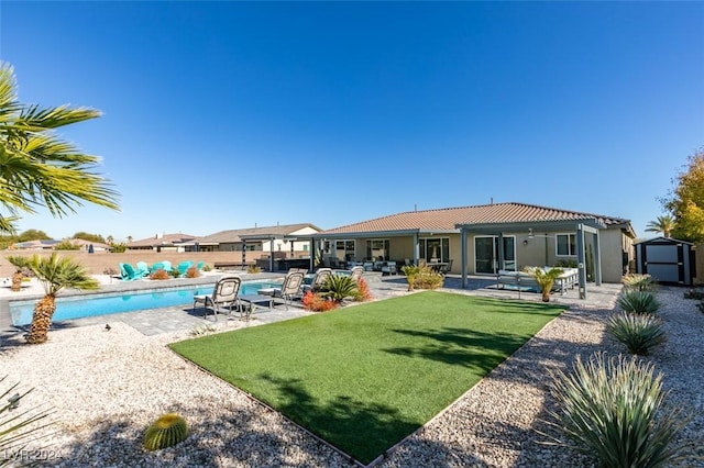 back of property featuring a fenced in pool, a patio area, and a storage unit